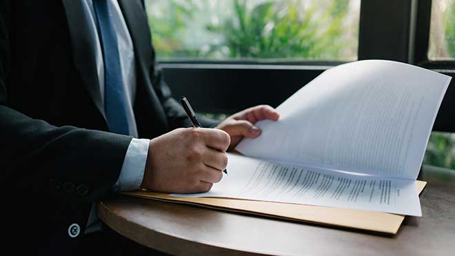 Homem de fato e gravata a assinar uma procuração.